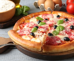 Photo of Tasty pizza and ingredients on grey wooden table, closeup