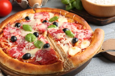 Photo of Tasty pizza with salami, cheese, basil and olives on grey wooden table, closeup