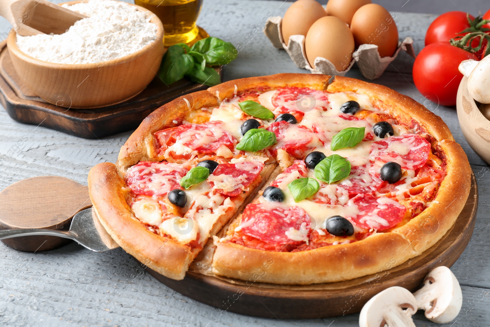 Tasty pizza and ingredients on grey wooden table, closeup Photo of Tasty pizza and ingredients on grey wooden table, closeup