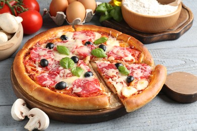 Photo of Tasty pizza and ingredients on grey wooden table, closeup