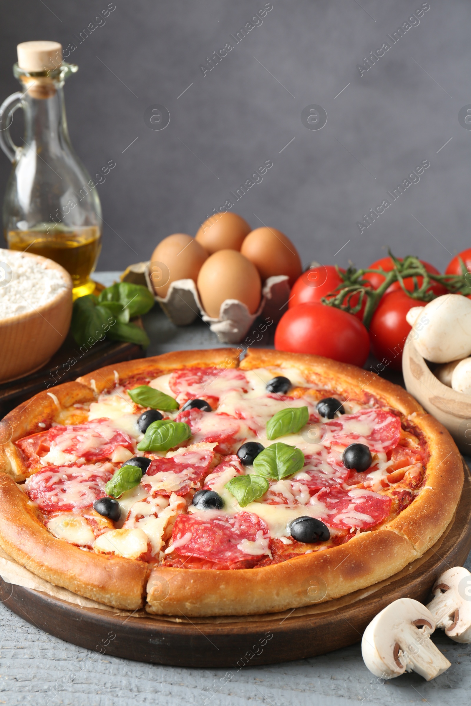 Tasty pizza and ingredients on grey wooden table, closeup Photo of Tasty pizza and ingredients on grey wooden table, closeup