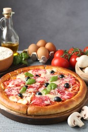 Photo of Tasty pizza and ingredients on grey wooden table, closeup