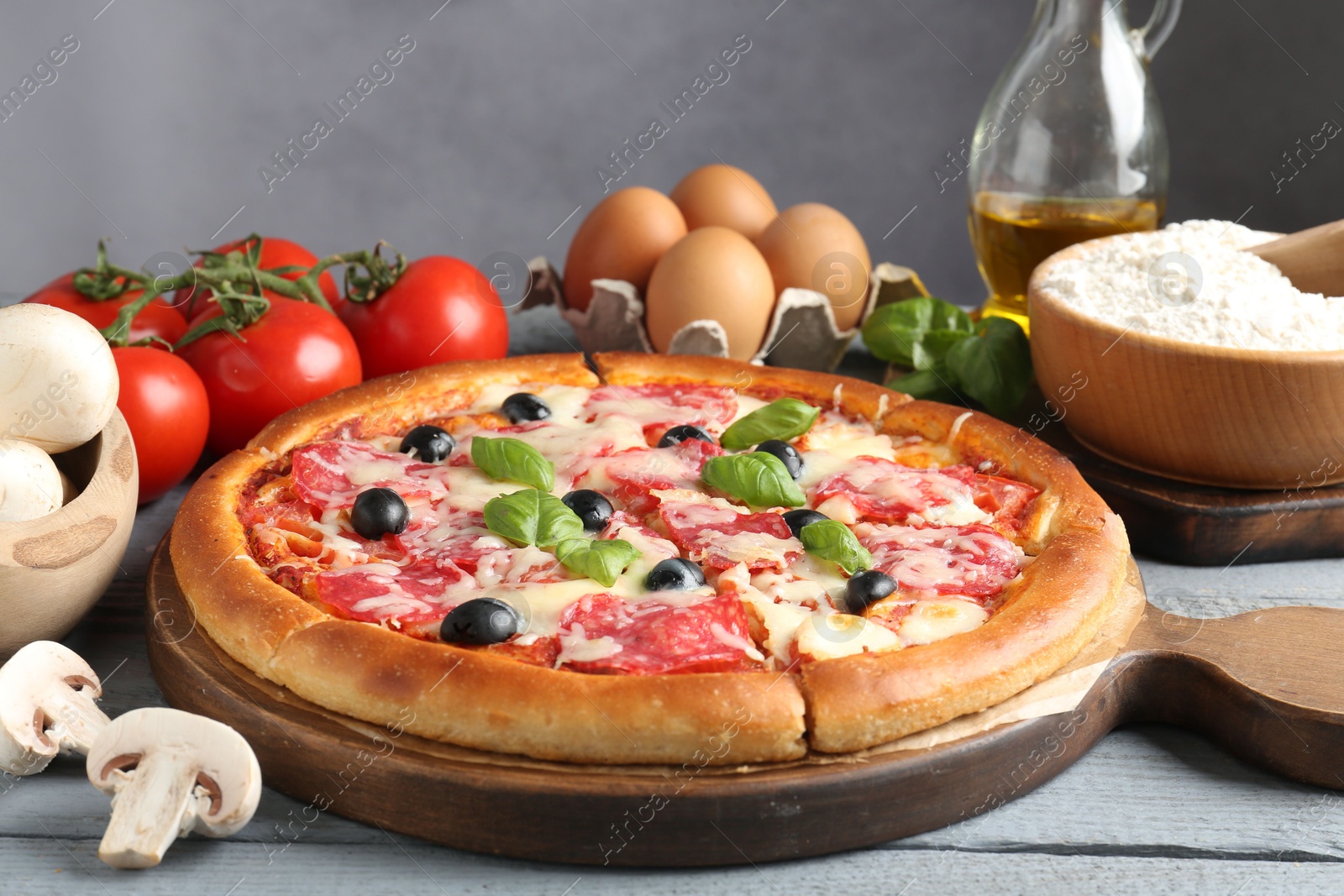 Tasty pizza and ingredients on grey wooden table, closeup Photo of Tasty pizza and ingredients on grey wooden table, closeup