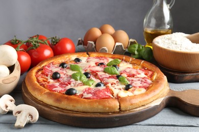 Photo of Tasty pizza and ingredients on grey wooden table, closeup