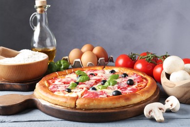 Photo of Tasty pizza and ingredients on grey wooden table, closeup