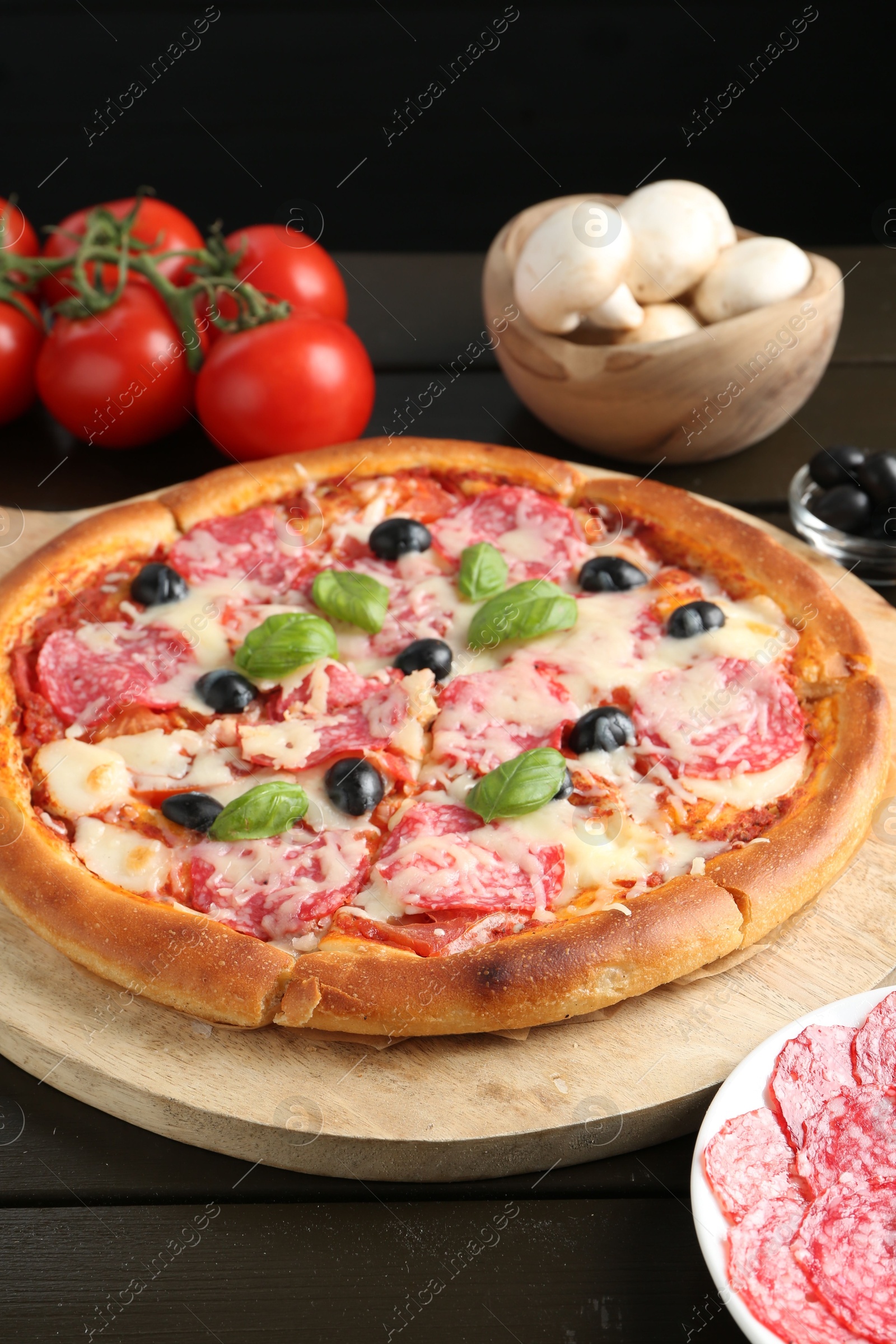 Tasty pizza and ingredients on black wooden table, closeup Photo of Tasty pizza and ingredients on black wooden table, closeup