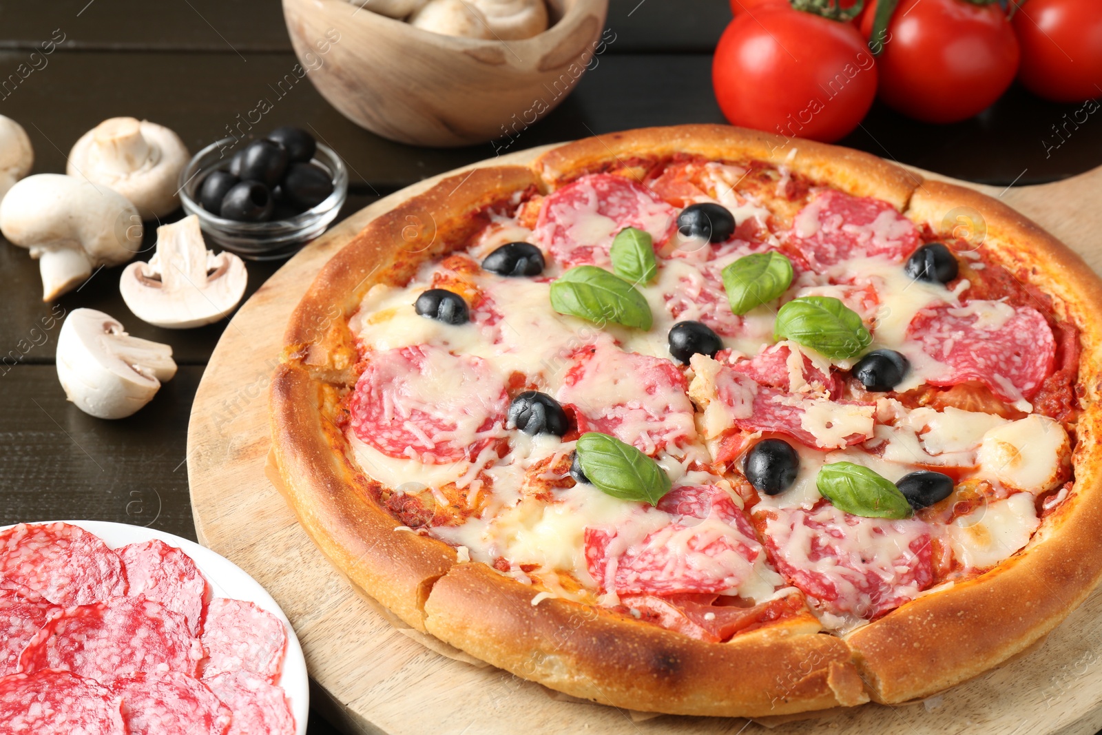 Tasty pizza and ingredients on black wooden table, closeup Photo of Tasty pizza and ingredients on black wooden table, closeup
