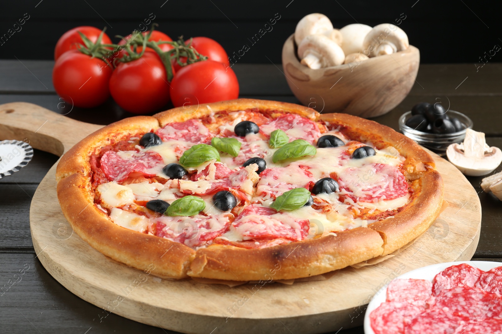 Tasty pizza and ingredients on black wooden table, closeup Photo of Tasty pizza and ingredients on black wooden table, closeup