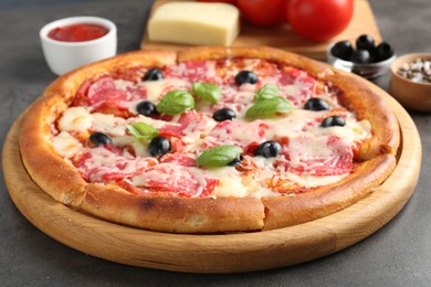 Photo of Tasty pizza and ingredients on grey table, closeup