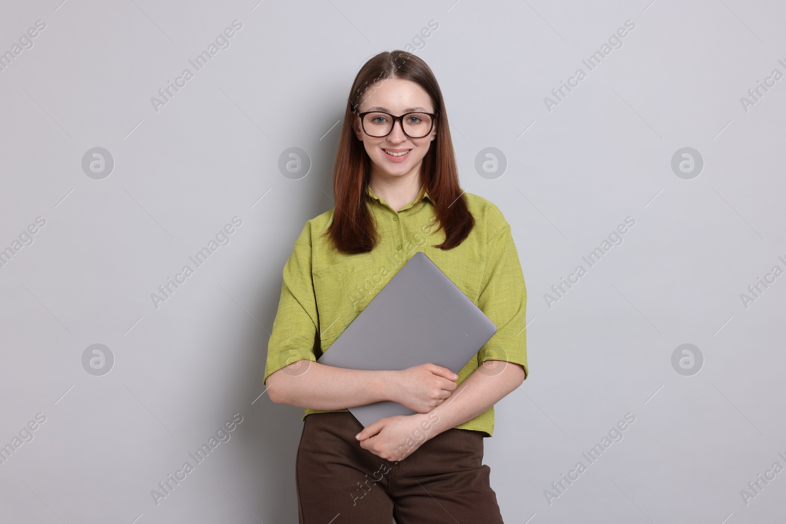 Photo of Happy teenage girl with laptop on light grey background