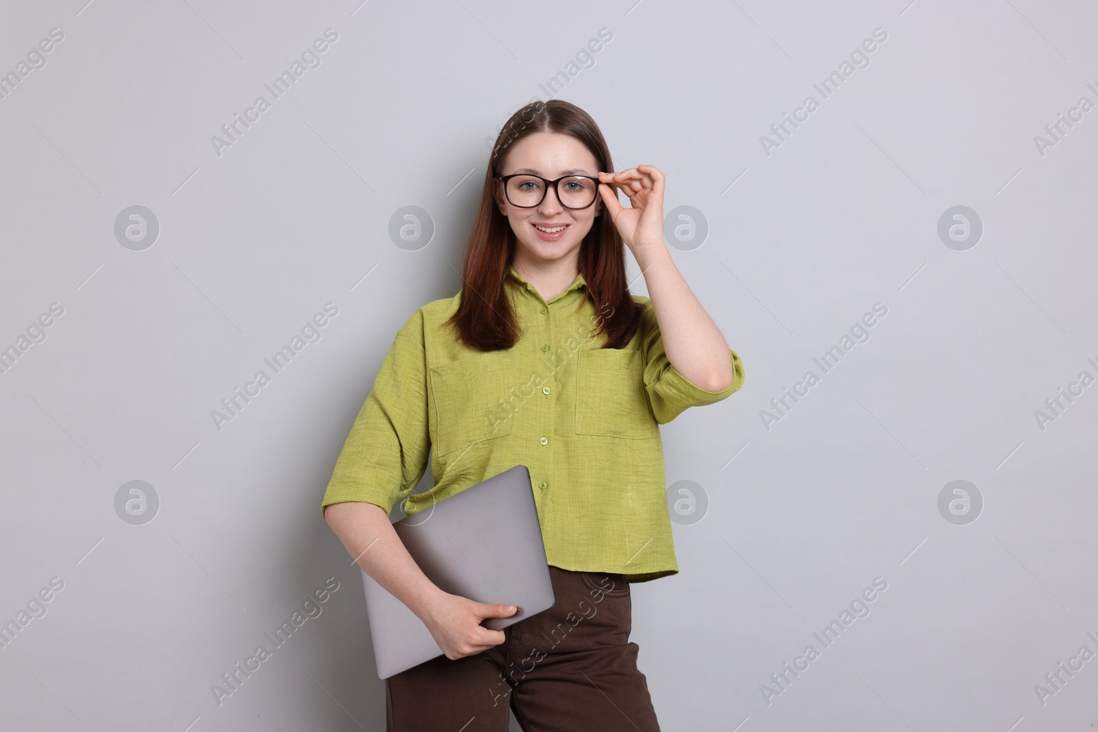 Photo of Happy teenage girl with laptop on light grey background