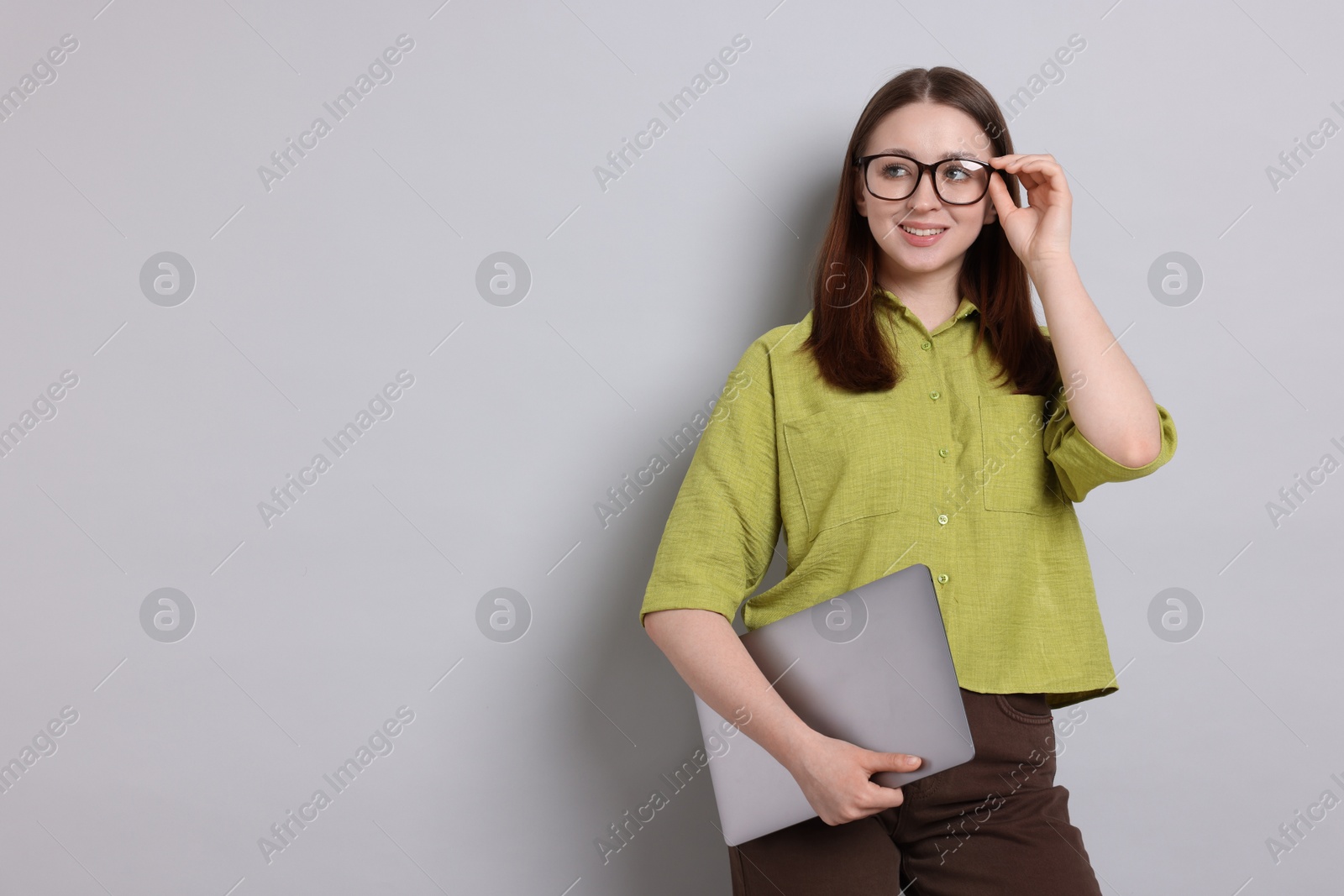 Happy teenage girl with laptop on light grey background, space for text Photo of Happy teenage girl with laptop on light grey background, space for text
