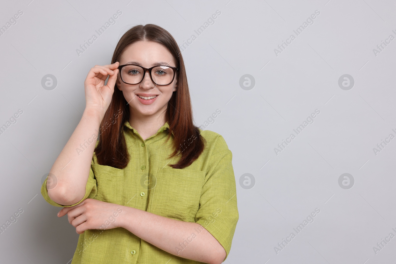 Happy teenage girl in glasses on light grey background, space for text Photo of Happy teenage girl in glasses on light grey background, space for text