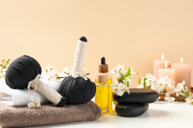 Photo of Spa composition with cosmetic products, beautiful flowers and burning candles on white table against beige background
