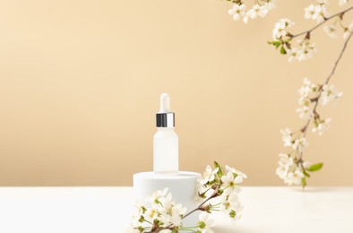 Photo of Stylish presentation of cosmetic product and twigs with beautiful flowers on beige background