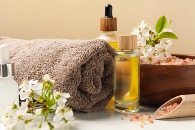 Photo of Spa composition with cosmetic products and beautiful flowers on white table, closeup