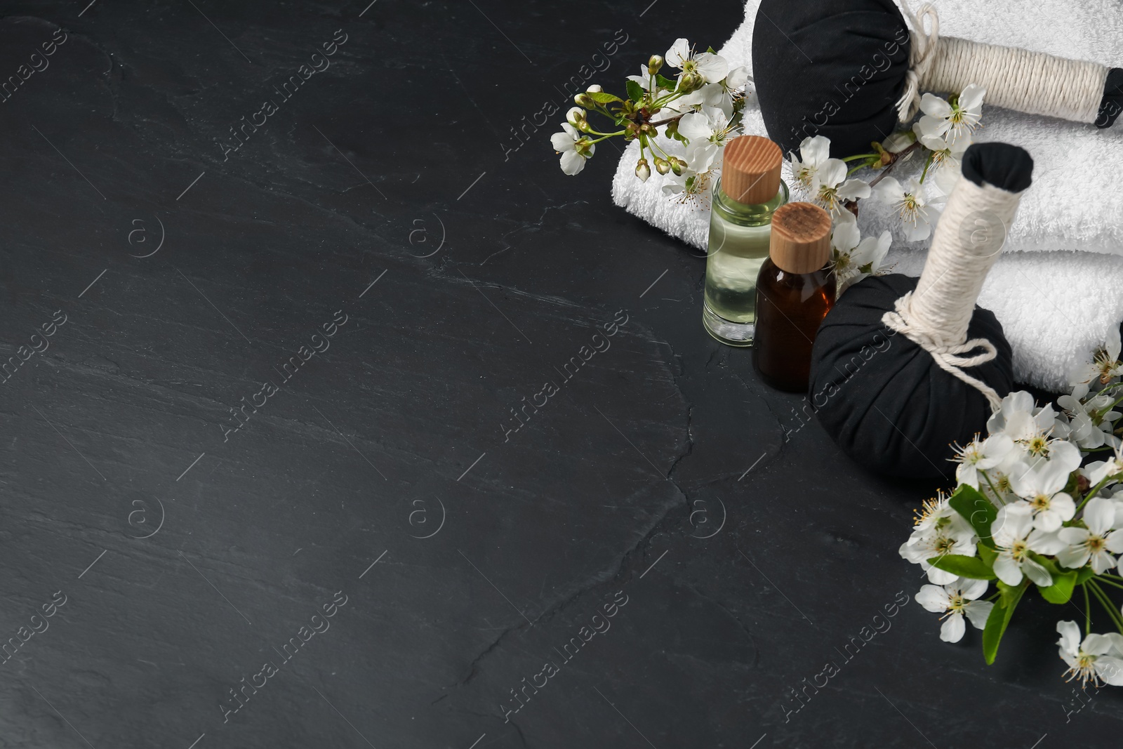 Spa composition with cosmetic products and beautiful flowers on black textured table, space for text Photo of Spa composition with cosmetic products and beautiful flowers on black textured table, space for text