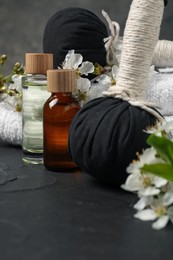 Photo of Spa composition with cosmetic products and beautiful flowers on black textured table, closeup