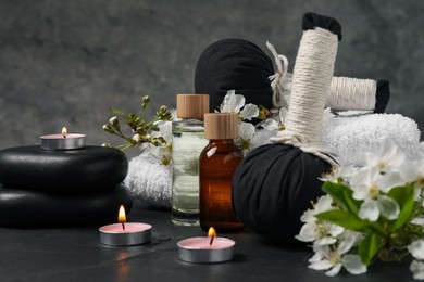 Photo of Spa composition with cosmetic products, burning candles and beautiful flowers on table against gray background, closeup