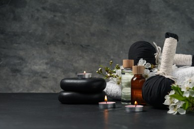 Photo of Spa composition with cosmetic products, burning candles and beautiful flowers on table against gray background, space for text