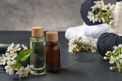 Photo of Spa composition with cosmetic products and beautiful flowers on black textured table, closeup