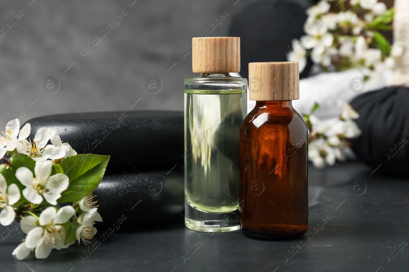 Spa composition with cosmetic products and beautiful flowers on black textured table, closeup Photo of Spa composition with cosmetic products and beautiful flowers on black textured table, closeup