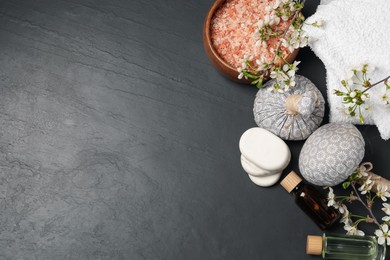 Photo of Spa composition with cosmetic products and beautiful flowers on black textured table, flat lay. Space for text
