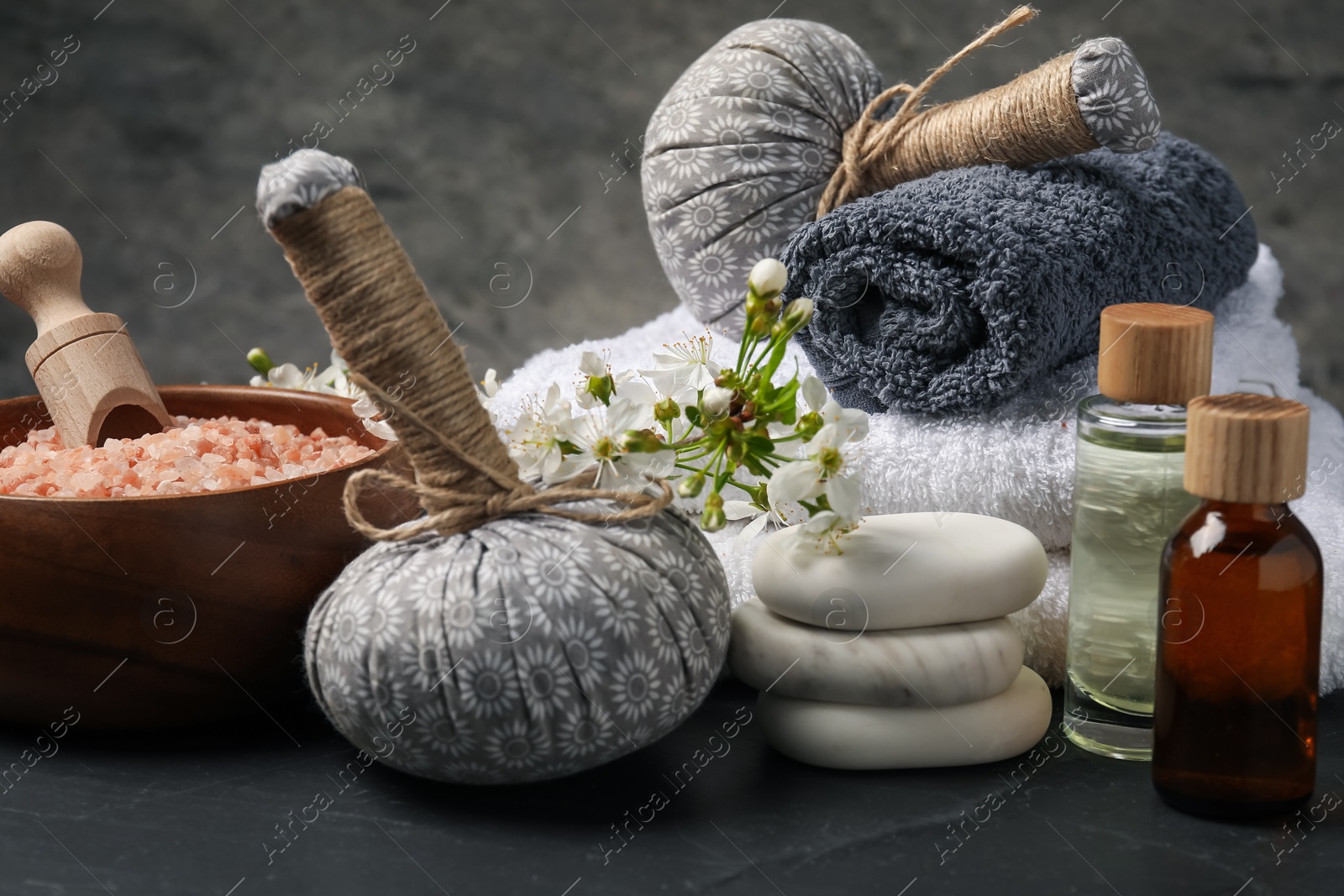 Spa composition with cosmetic products and beautiful flowers on black textured table, closeup Photo of Spa composition with cosmetic products and beautiful flowers on black textured table, closeup