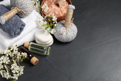 Photo of Spa composition with cosmetic products and beautiful flowers on black textured table, above view. Space for text