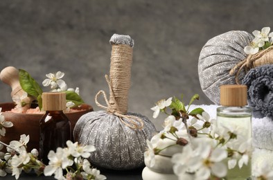 Photo of Spa composition with cosmetic products, burning candles and beautiful flowers on table against gray background, closeup