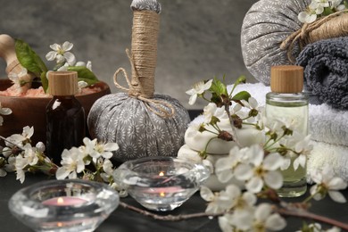 Photo of Spa composition with cosmetic products, burning candles and beautiful flowers on table, closeup