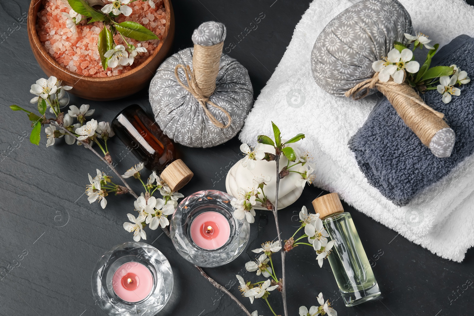 Spa composition with cosmetic products, burning candles and beautiful flowers on black textured table, flat lay Photo of Spa composition with cosmetic products, burning candles and beautiful flowers on black textured table, flat lay