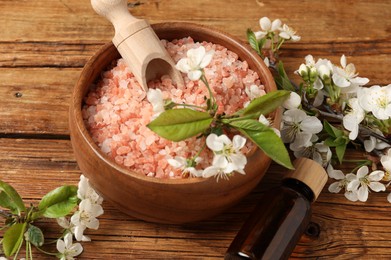 Photo of Spa composition with sea salt, cosmetic product and beautiful flowers on wooden table, closeup