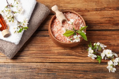Photo of Spa composition with sea salt, cosmetic product and beautiful flowers on wooden table, flat lay