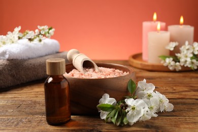Photo of Spa composition with sea salt, beautiful flowers and burning candles on wooden table, selective focus