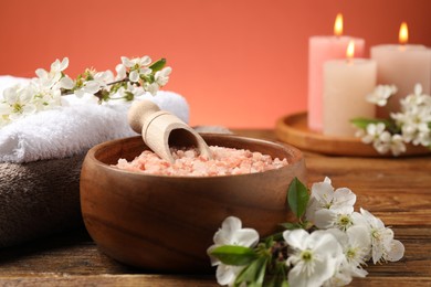 Photo of Spa composition with sea salt, beautiful flowers and burning candles on wooden table, selective focus