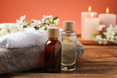 Photo of Spa composition with cosmetic products, beautiful flowers and burning candles on wooden table, selective focus