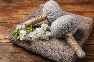 Photo of Herbal bags, towel and twig with beautiful flowers on wooden table, closeup