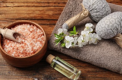 Photo of Spa products and twig with beautiful flowers on wooden table, above view