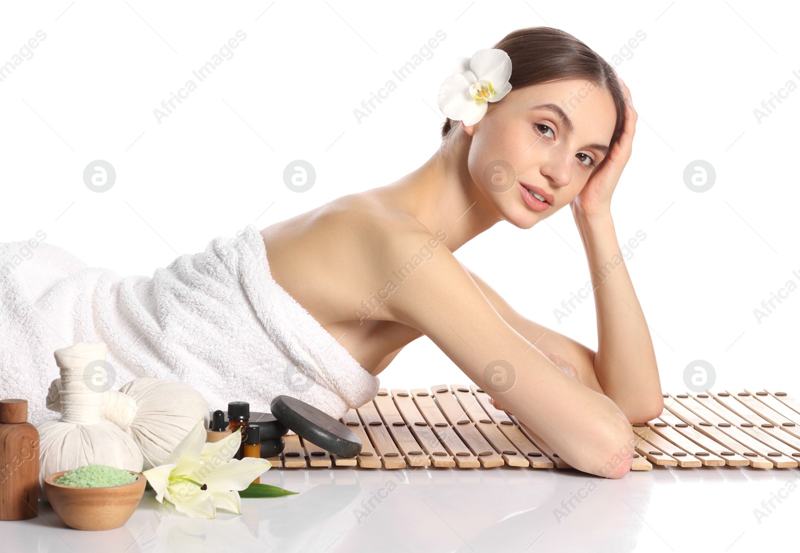 Photo of Beautiful woman posing on bamboo mat against white background. Spa products and flowers on mirror surface
