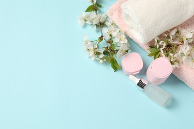 Photo of Spa composition with cosmetic products, towels and beautiful flowers on light blue background, flat lay. Space for text