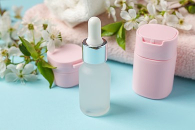 Photo of Spa composition with cosmetic products, towels and beautiful flowers on light blue background, closeup