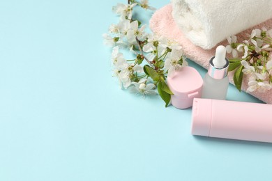 Photo of Spa composition with cosmetic products, towels and beautiful flowers on light blue background, space for text