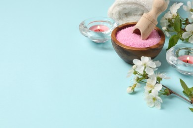 Photo of Spa composition with sea salt, burning candles, towel and beautiful flowers on light blue background, space for text