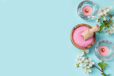 Photo of Spa composition with sea salt, burning candles and beautiful flowers on light blue background, flat lay. Space for text