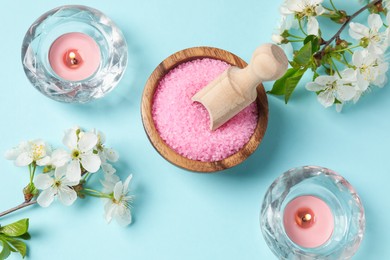 Photo of Spa composition with sea salt, burning candles and beautiful flowers on light blue background, flat lay