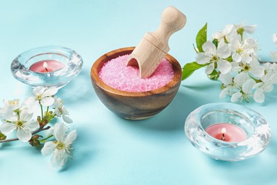 Photo of Spa composition with sea salt, burning candles and beautiful flowers on light blue background, closeup