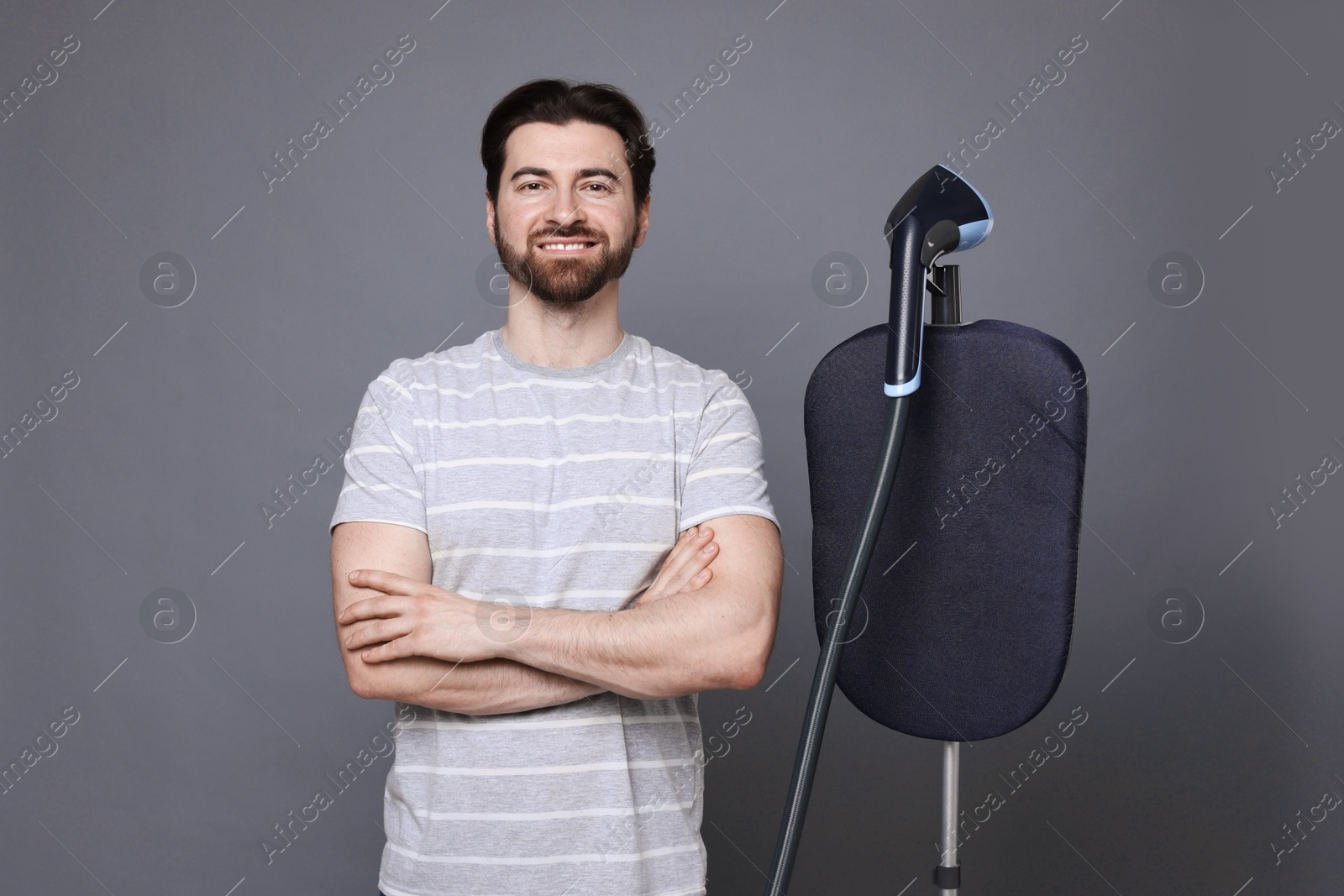Man with stand steamer on grey background Photo of Man with stand steamer on grey background