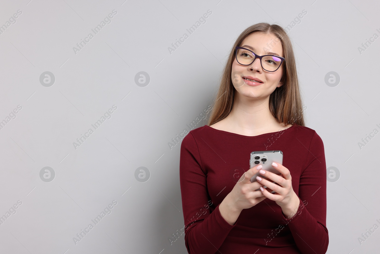 Teenage girl with smartphone on light grey background. Space for text Photo of Teenage girl with smartphone on light grey background. Space for text
