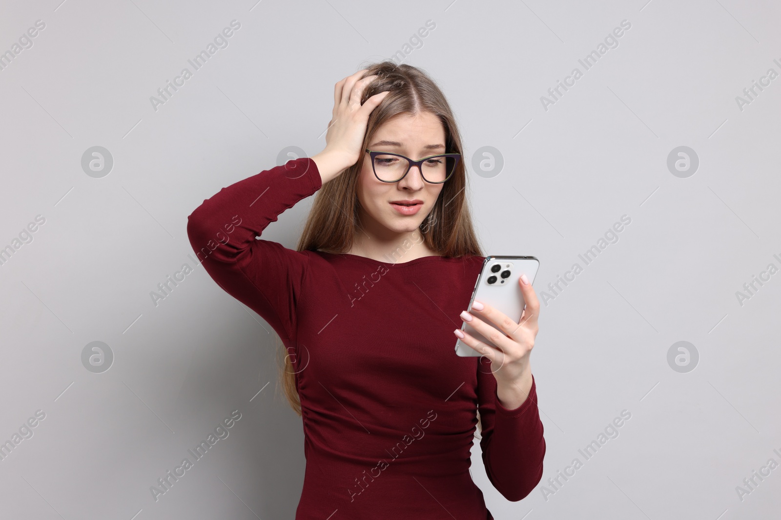 Teenage girl with smartphone on light grey background Photo of Teenage girl with smartphone on light grey background